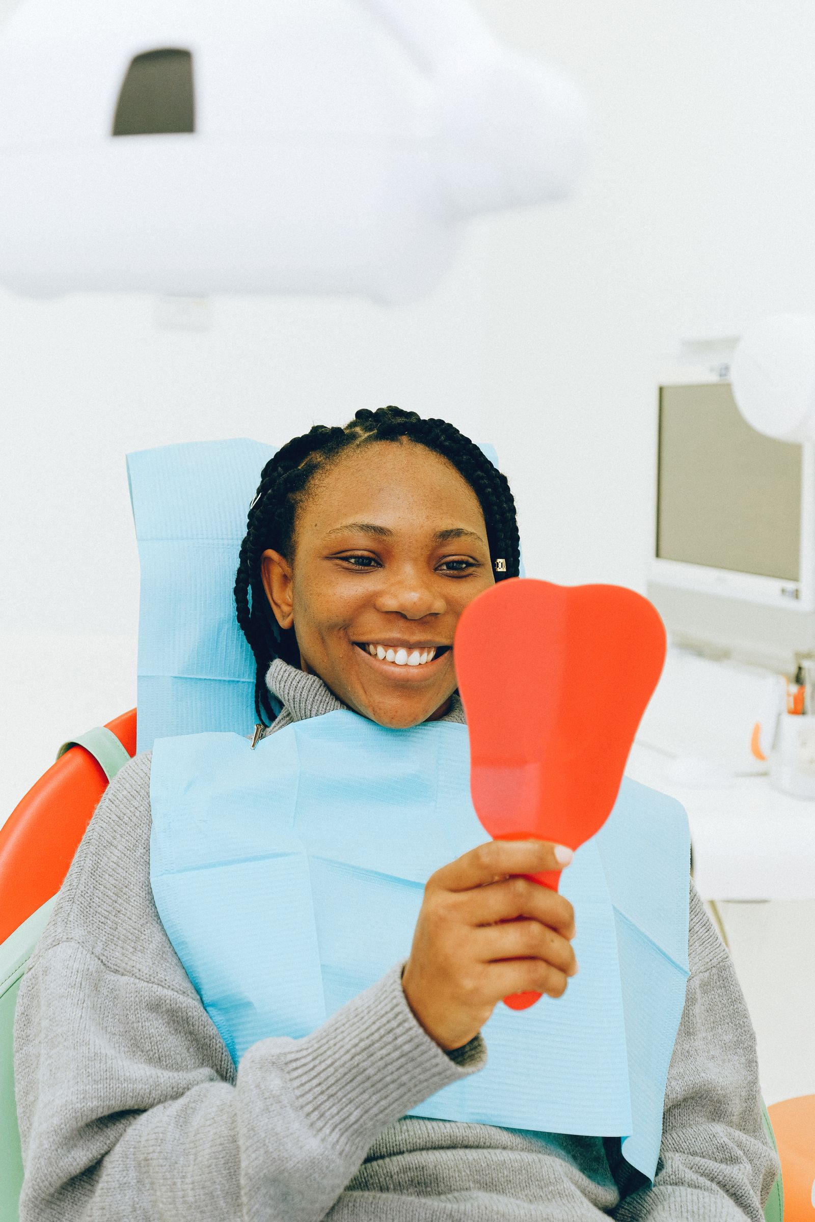 Smiling woman checking her teeth in a hand mirror
