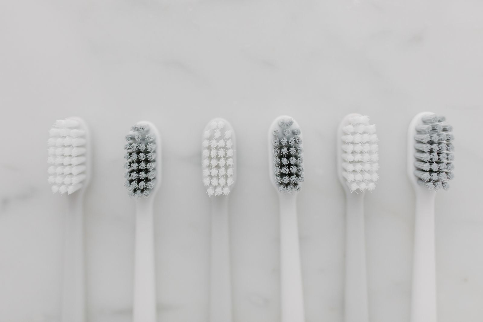 Clean white toothbrushes lined up on marble